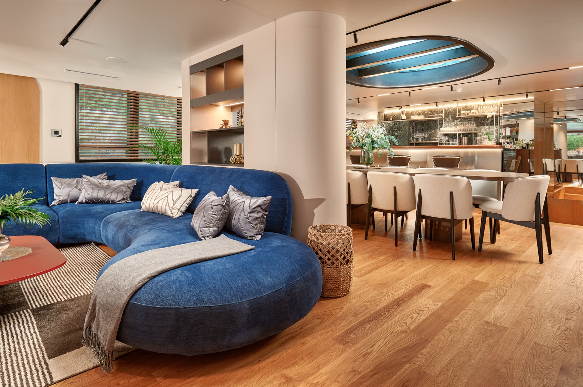 Modern interior with curved blue sofa, dining area, and wood flooring