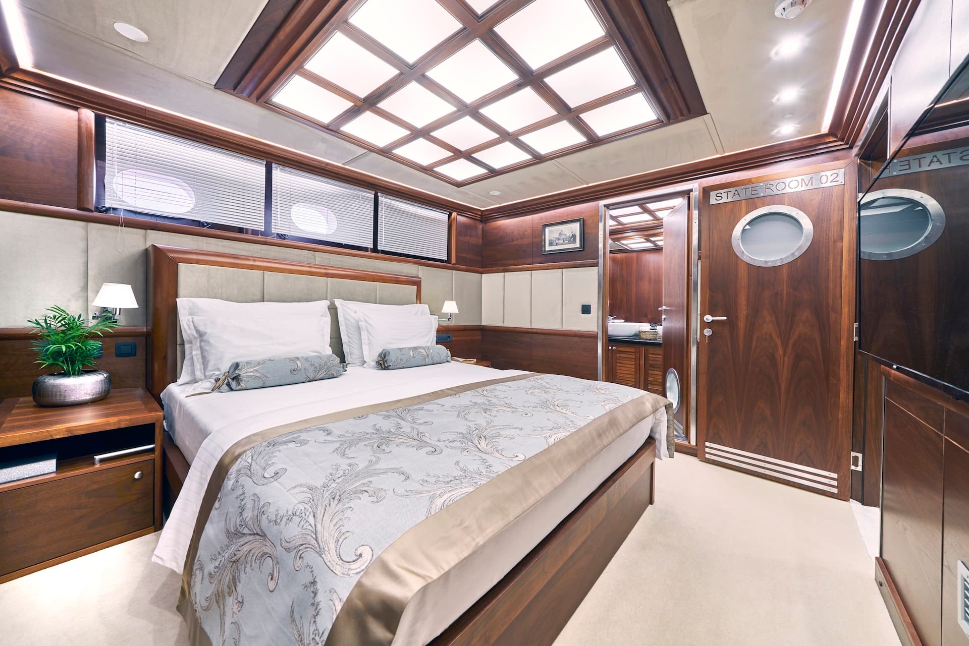 State Room 02 cabin interior with wood paneling, large bed, and illuminated ceiling on Lady Gita yacht.