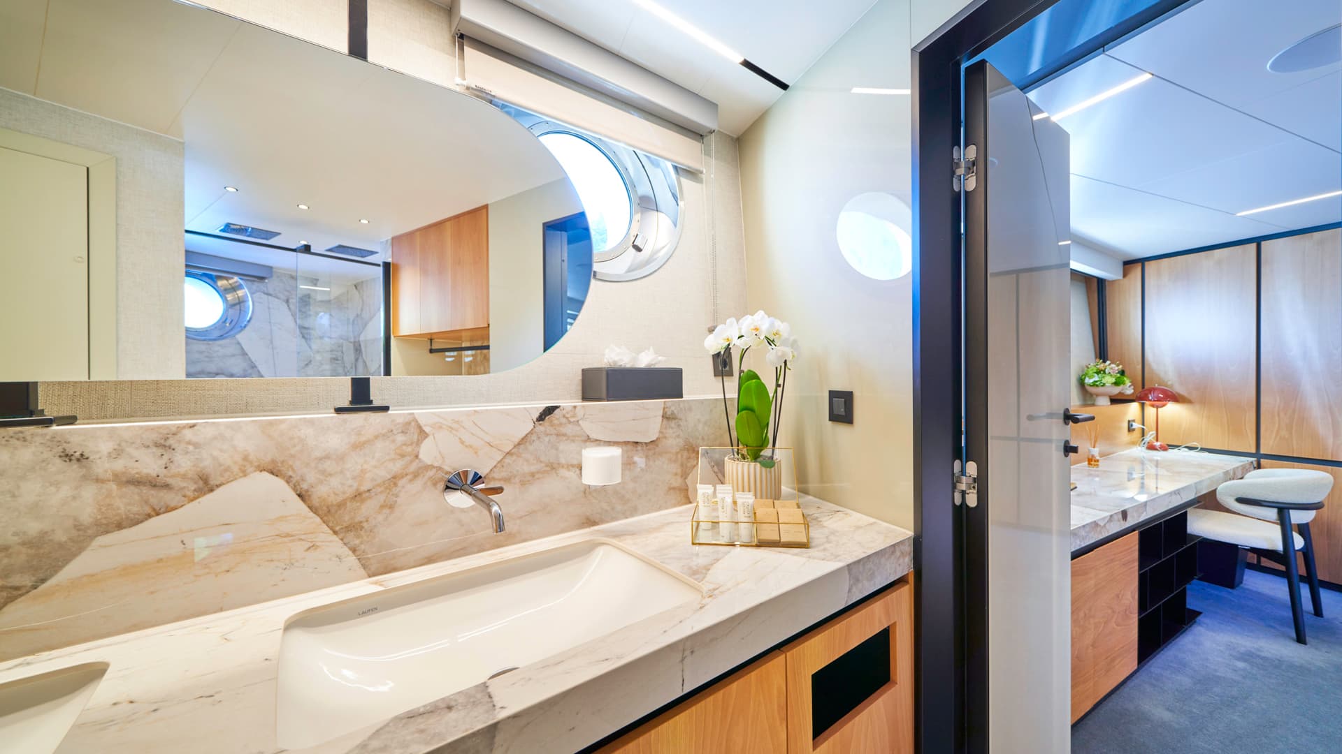 Modern bathroom vanity with marble countertop, vessel sink, and round mirror showing a porthole window.