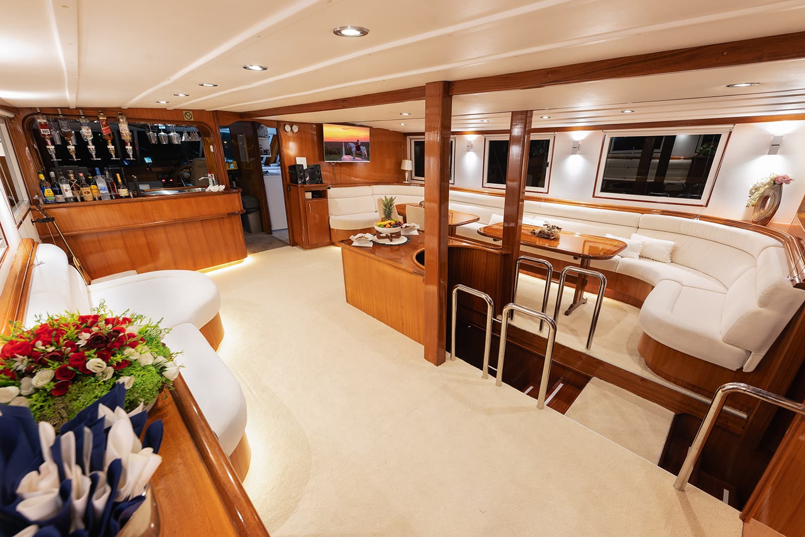 Luxurious yacht interior with wood paneling, white leather seating, bar area, and carpeted floor.