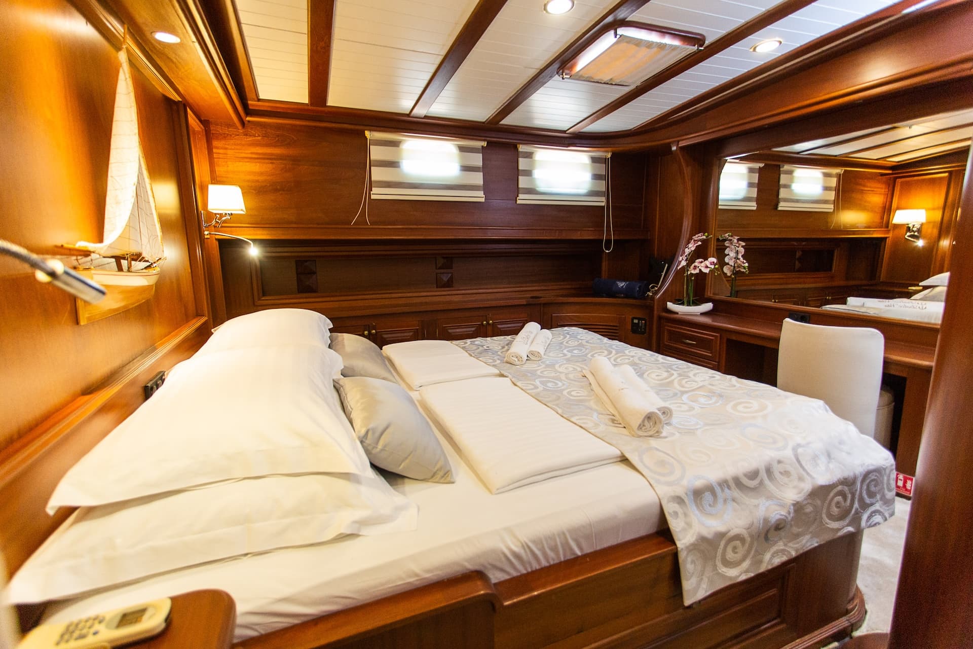 Double bedroom cabin with wood paneling, white linens, and model sailboat decor.