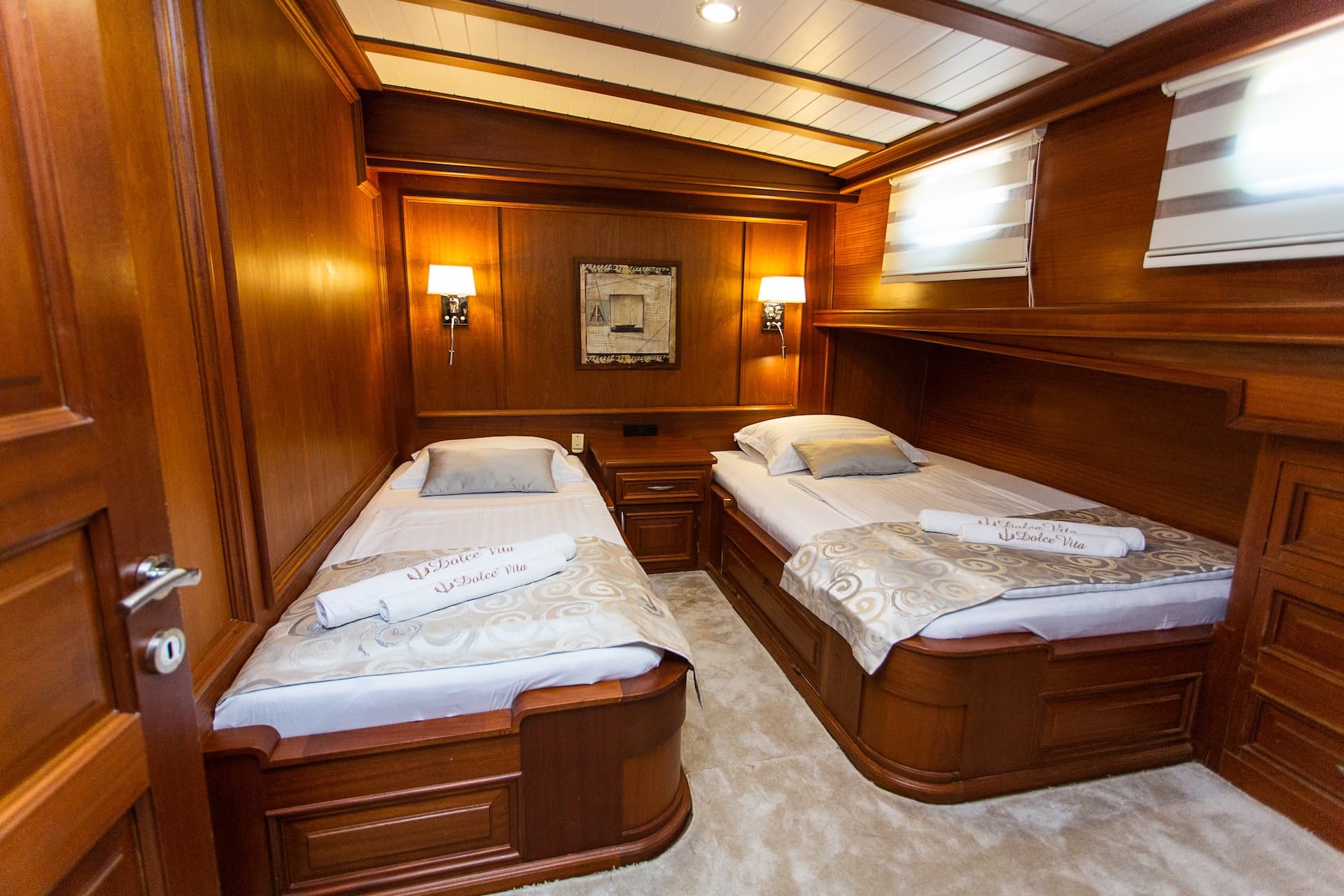 Twin cabin interior with rich wood paneling, two single beds, and soft lighting.