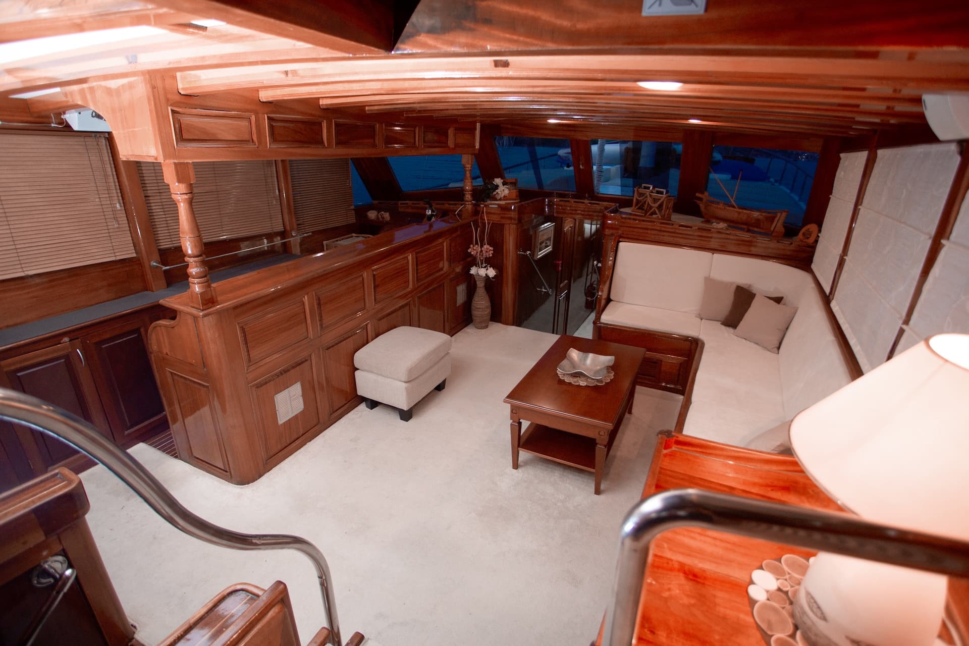 Interior salon of a yacht featuring rich wood paneling, white seating, and a low coffee table.