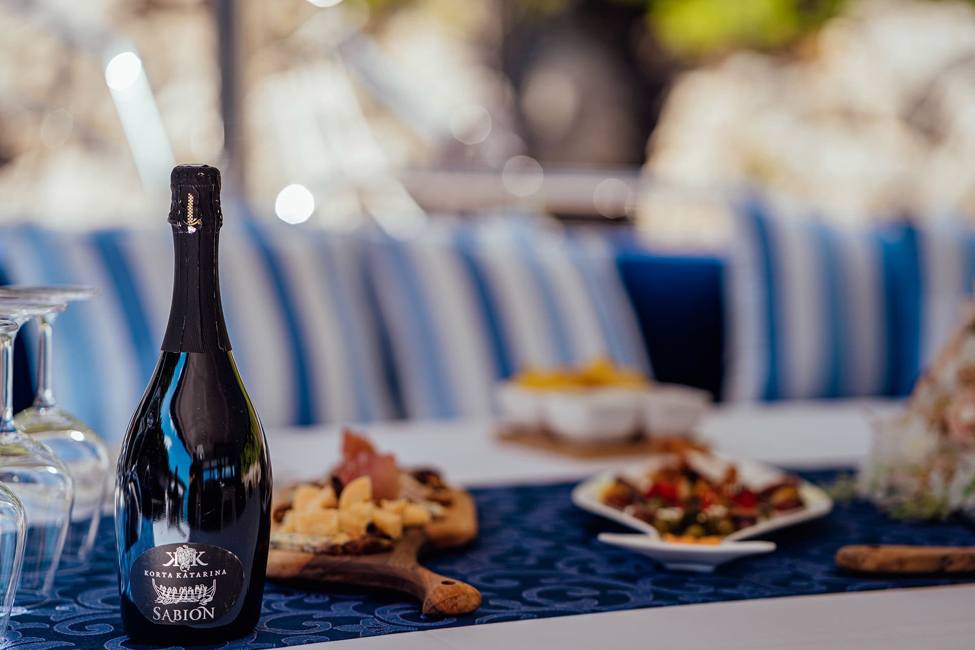 Sparkling wine bottle with cheese and charcuterie board on outdoor dining table
