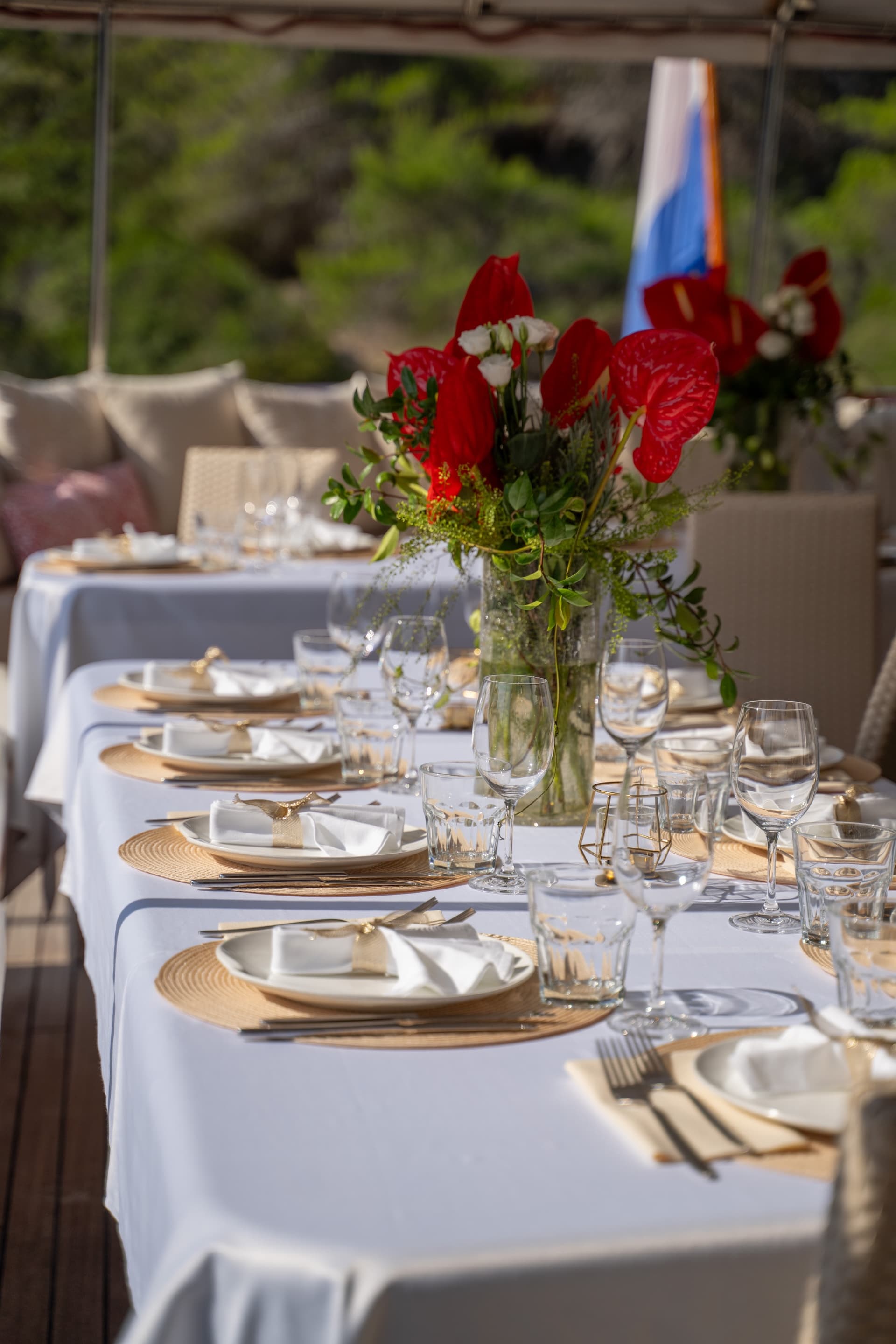 Dining table set on deck of Gulet Barbara with red flower centerpiece