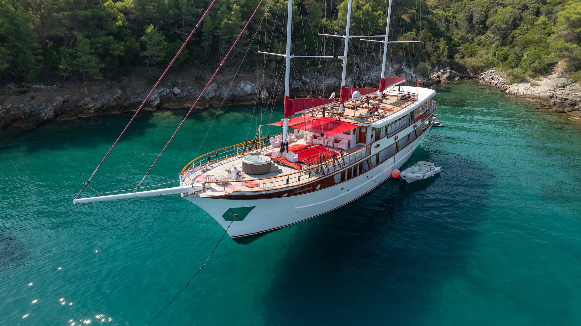 Gulet Barbara boat anchored in turquoise cove with forested rocky coastline.