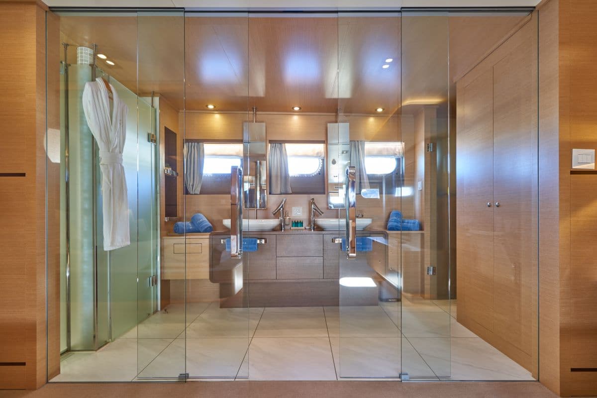 Luxury yacht bathroom with dual sinks, glass shower enclosure, and wood paneling