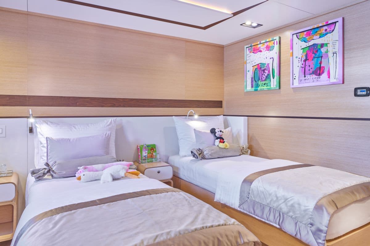 Twin beds in a modern cabin with light wood paneling and colorful artwork.