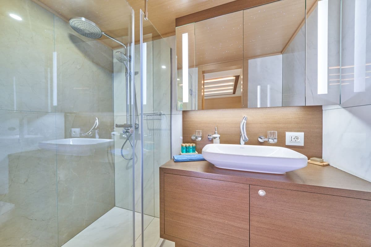 Modern bathroom vanity with vessel sink, illuminated mirror, and glass-enclosed shower stall