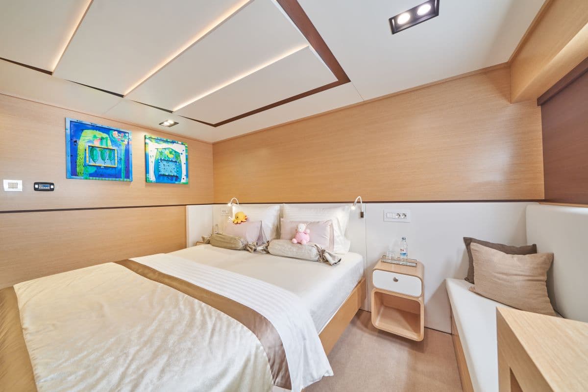 Cabin bedroom with wood paneling, white bedding, and two bright blue abstract paintings.