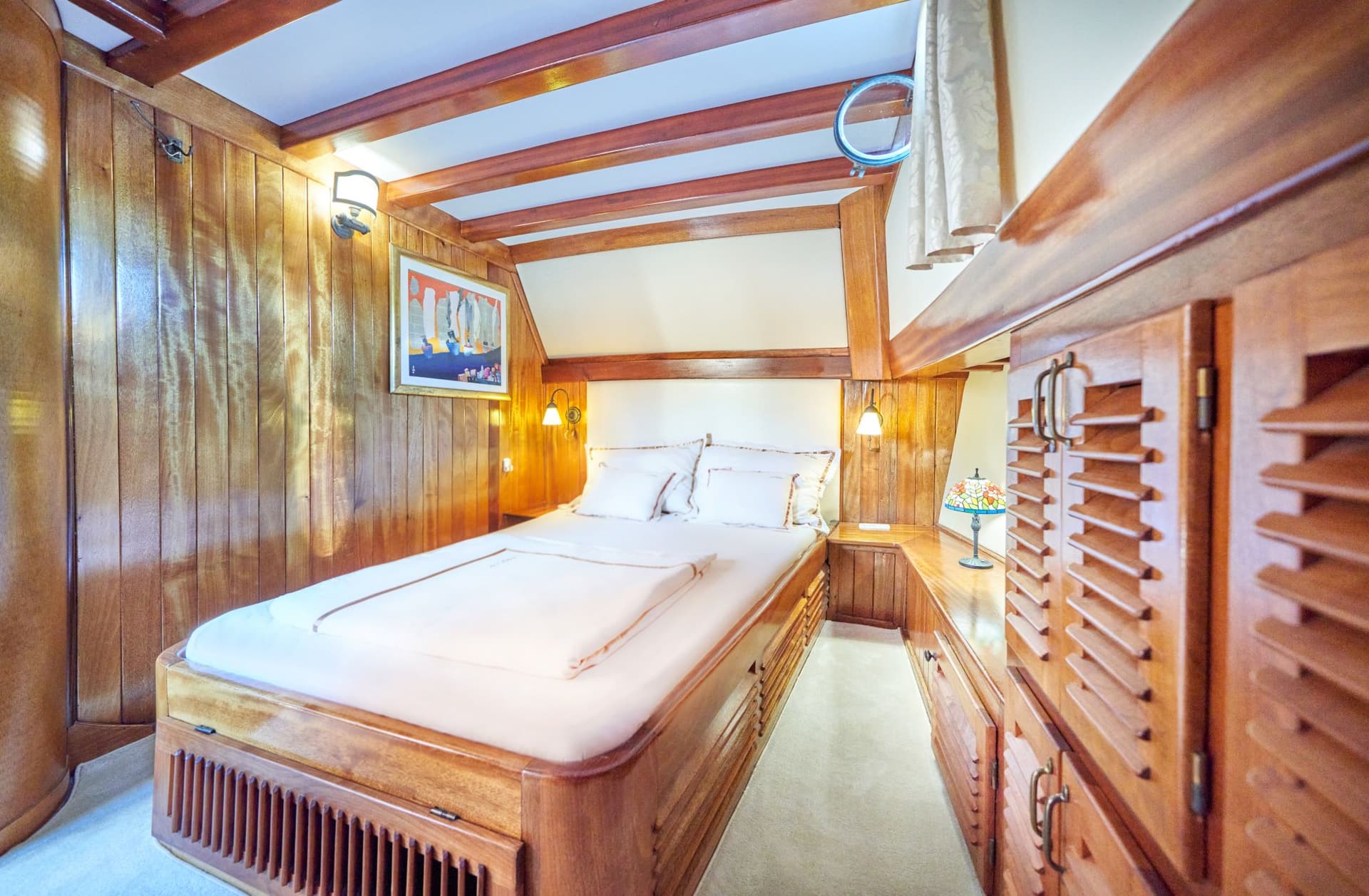 Master bedroom cabin with wood paneling, built-in bed, and louvered storage cabinets.