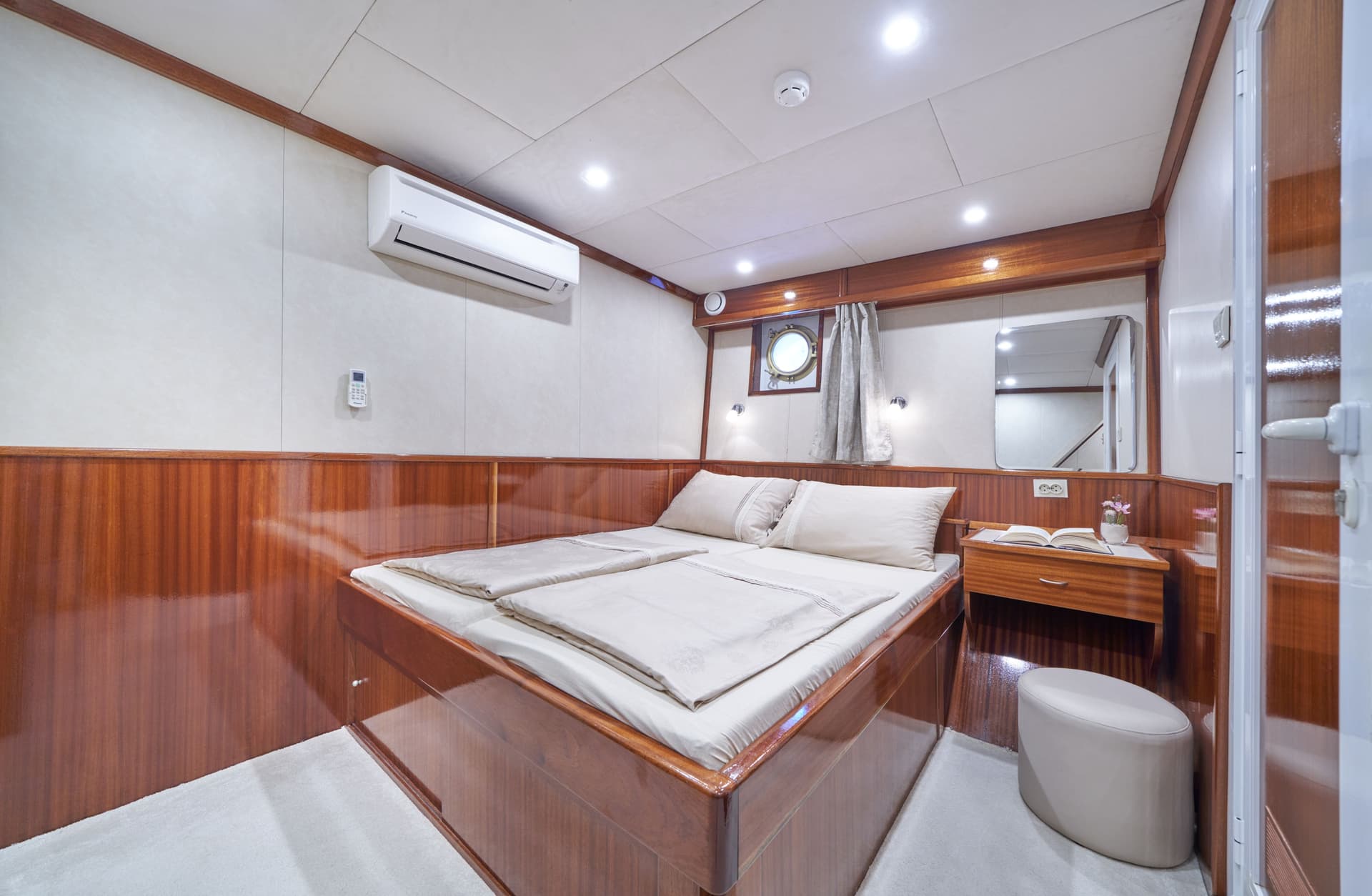 Double cabin interior with double bed, wood paneling, and porthole window, likely on a boat.