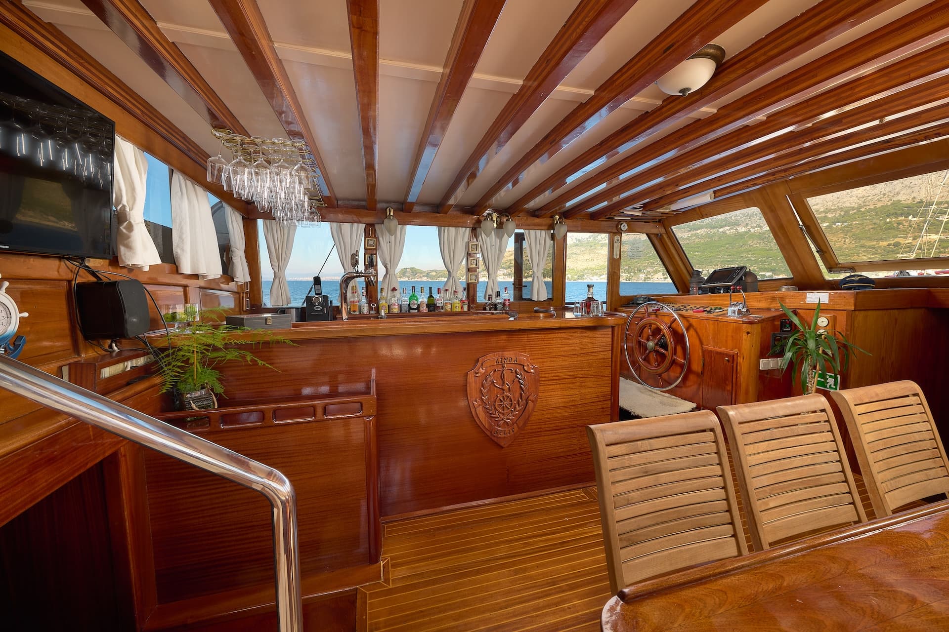 Wooden yacht interior bar area with helm station and view of coastline and sea
