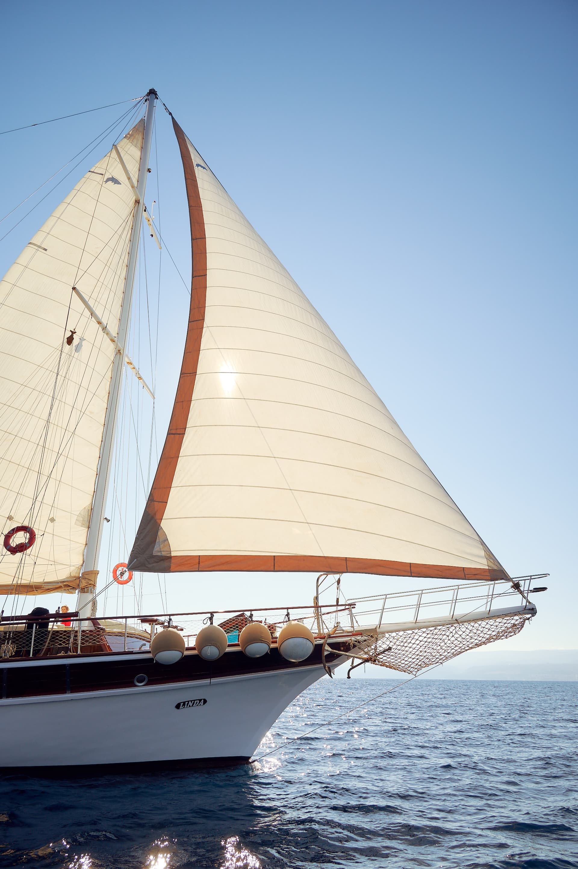 Sailboat named Linda sailing on deep blue water under a clear sky