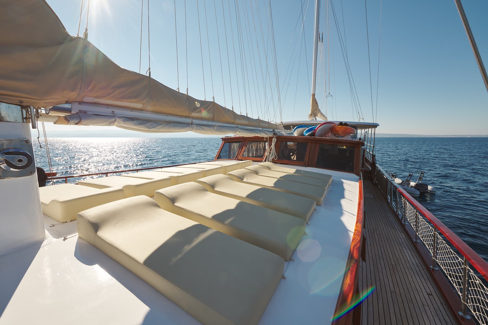 Sunbeds on the deck of a sailboat cruising on sparkling blue sea water