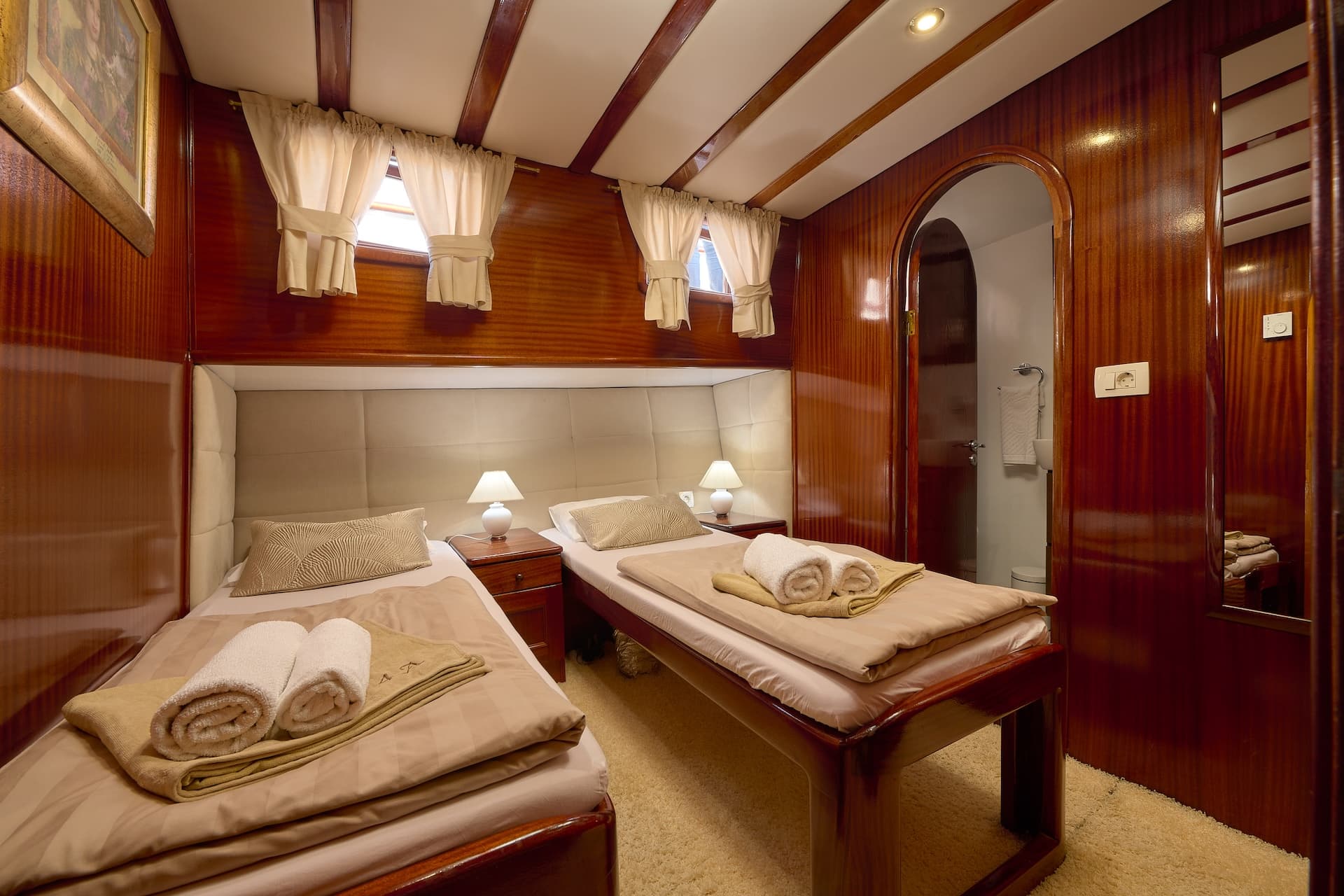 Twin cabin interior with polished wood paneling, two single beds, and beige carpeting.