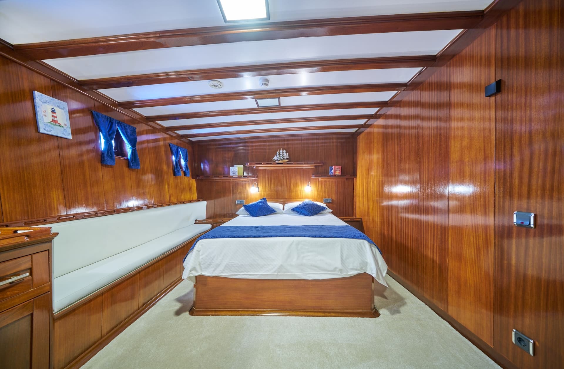 Cabin bedroom with wood paneling, white carpet, and double bed with blue accents
