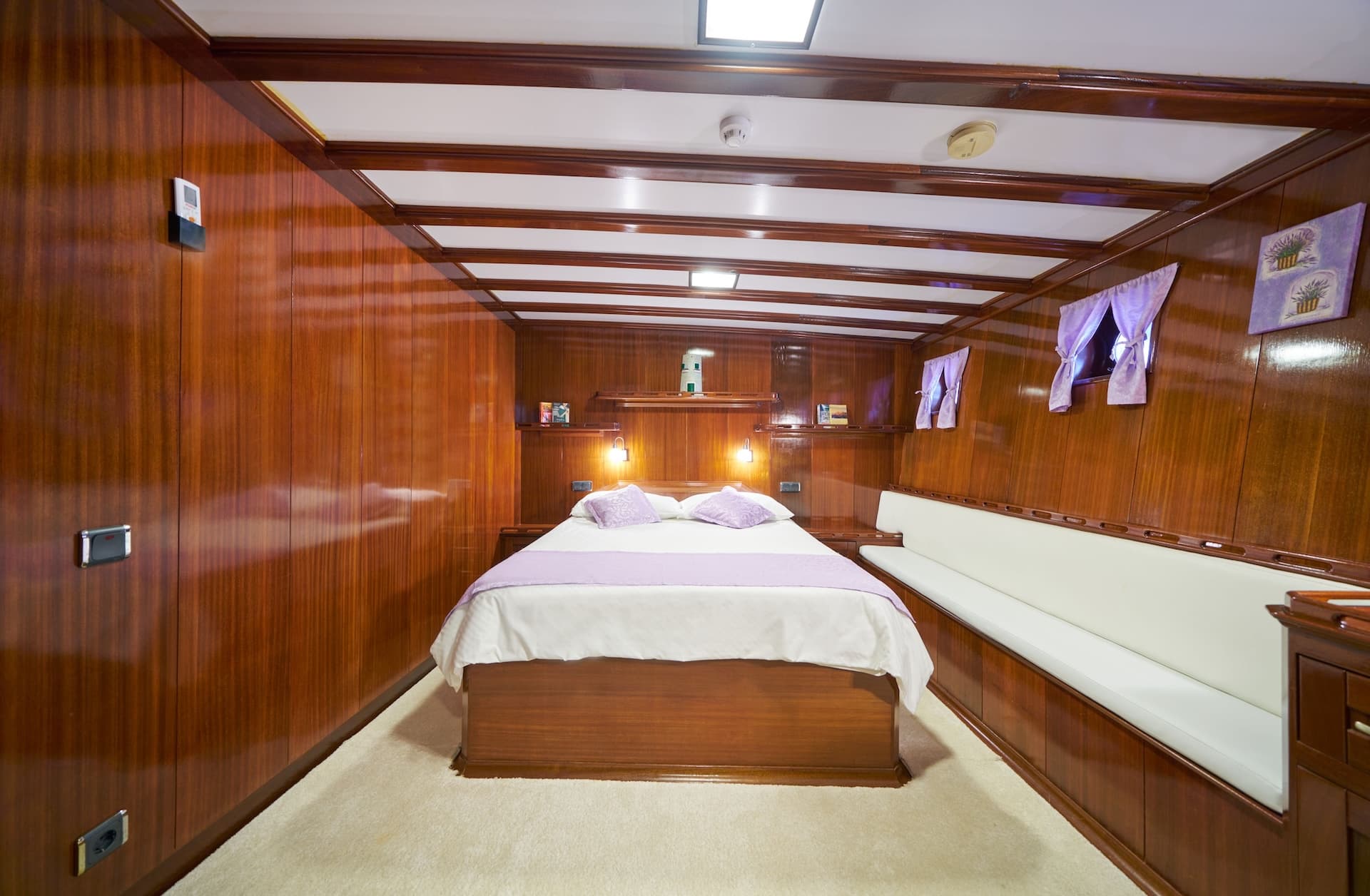 Double cabin interior with wood paneling, white carpet, and purple accents on a boat
