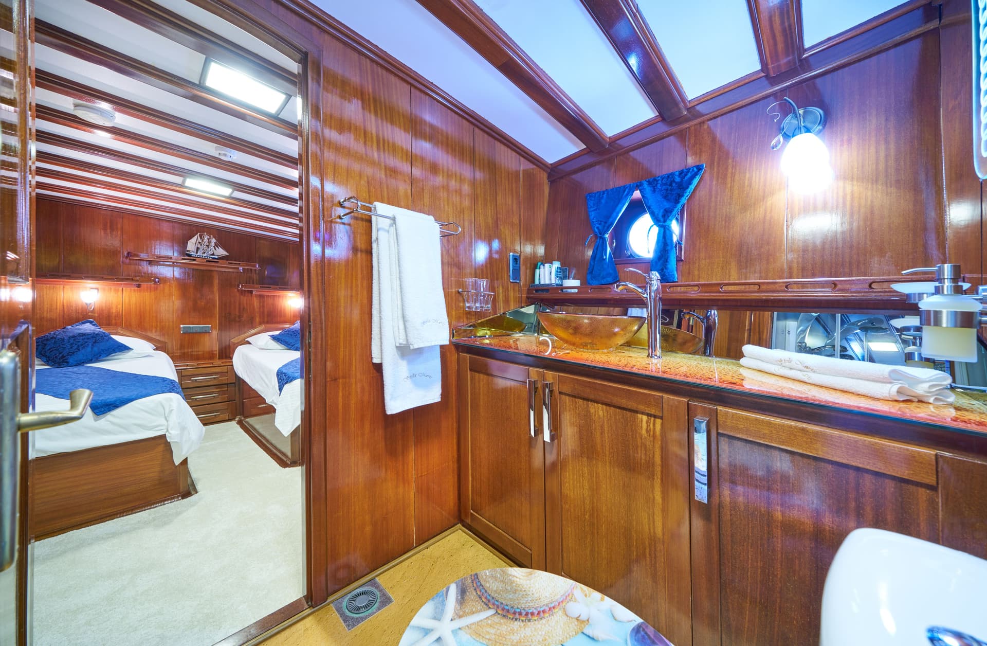 Boat cabin interior with rich wood paneling, vanity, and view into a bedroom.