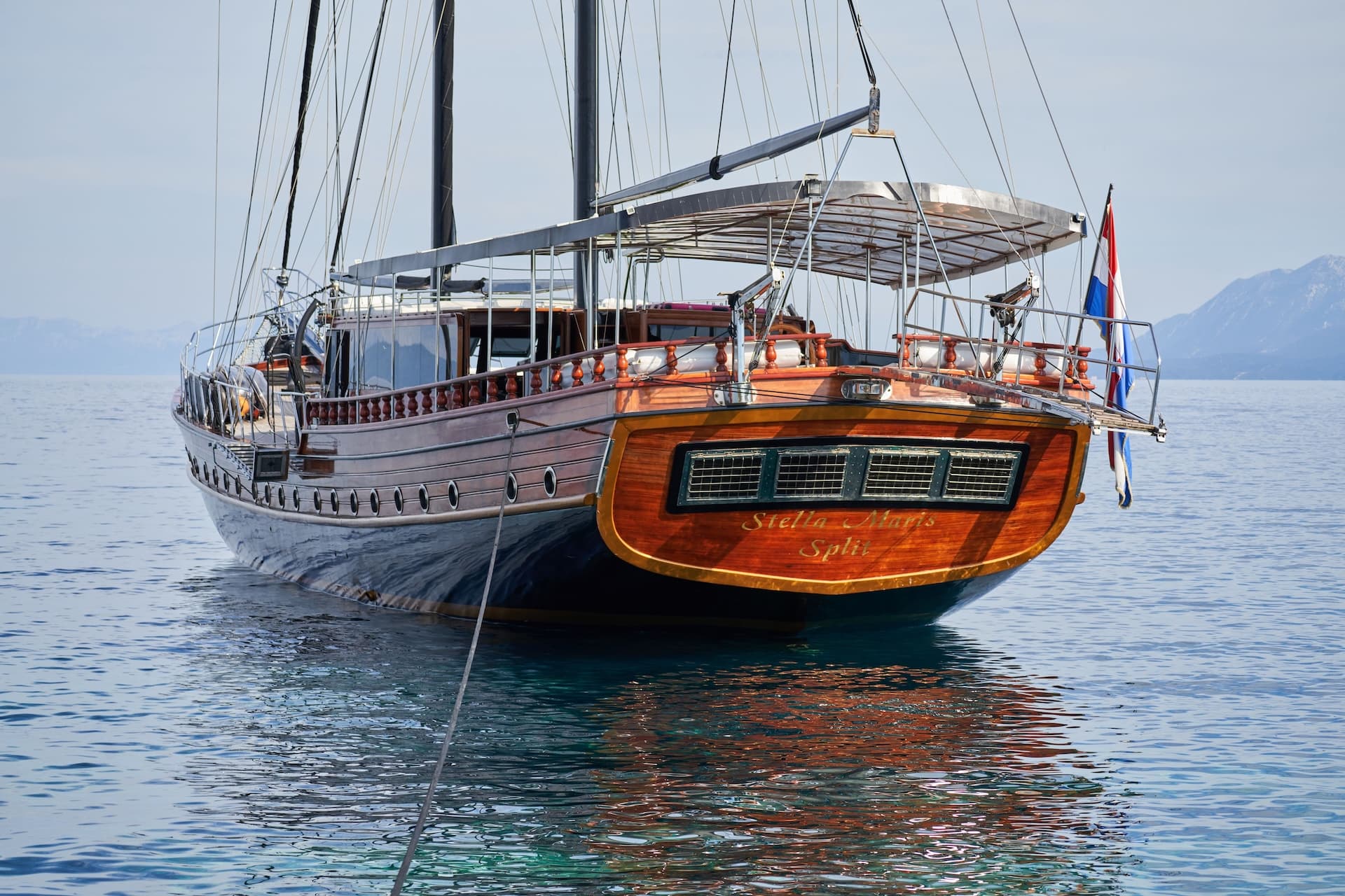 Wooden yacht Stella Maris from Split floating on calm blue sea near mountains
