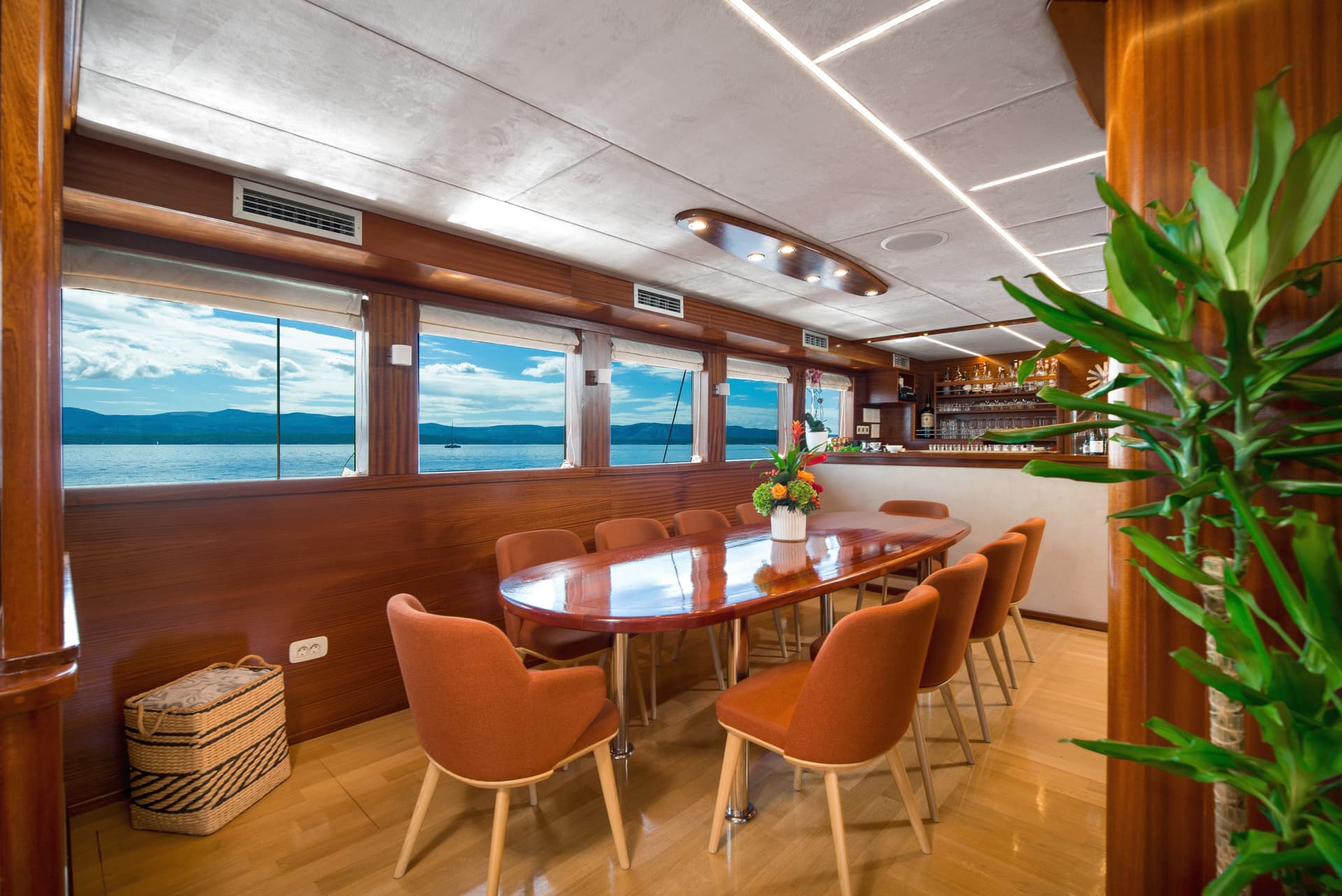 Dining area with wood paneling and view of blue water and mountains from a boat.