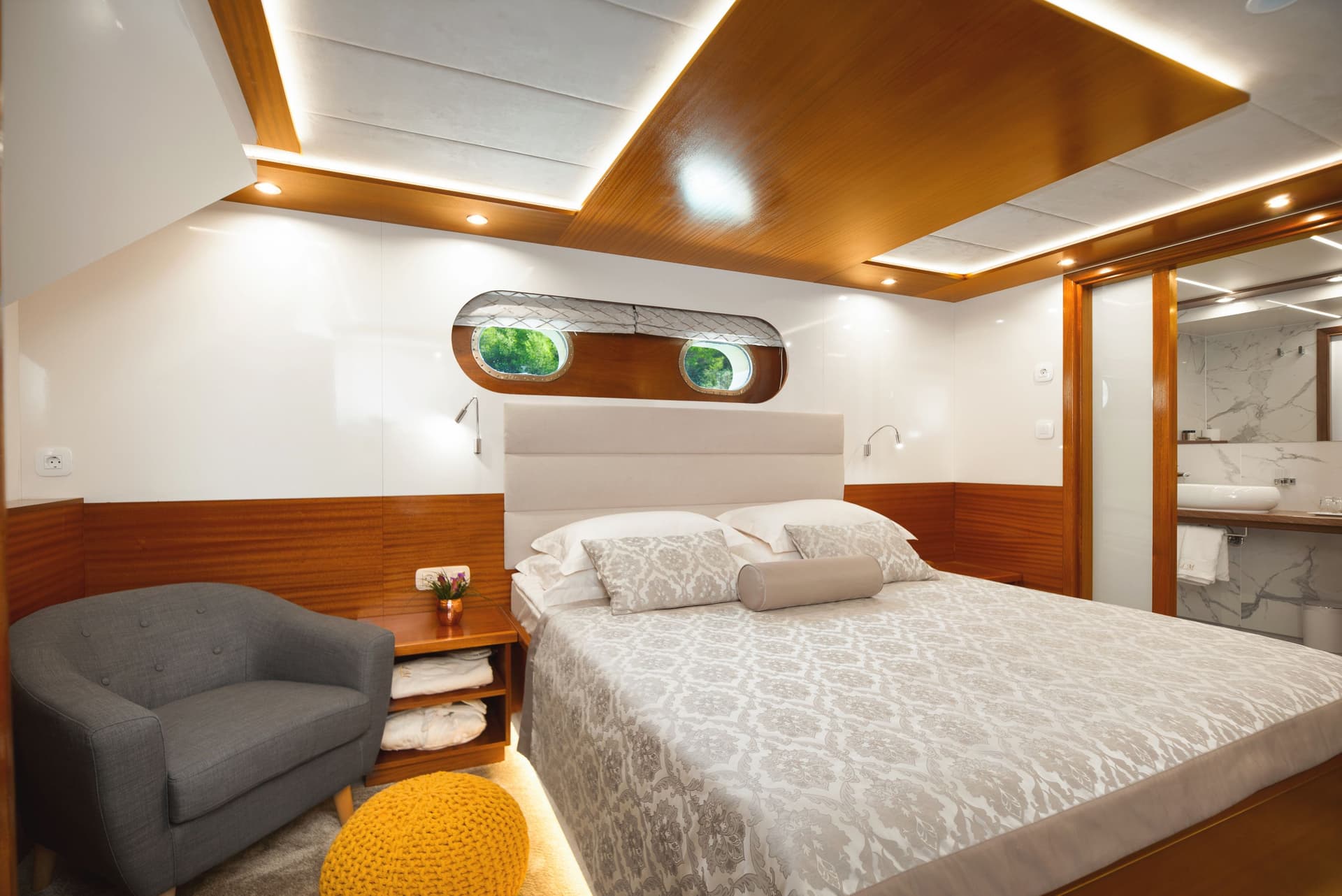 Double room cabin interior with porthole windows showing greenery, wood trim, and modern lighting.