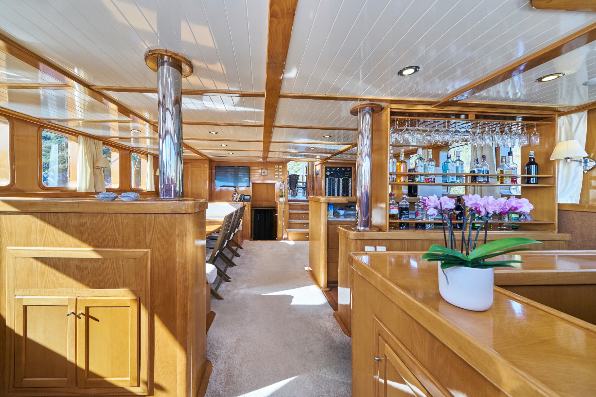 Interior of a yacht cabin with wood paneling, a bar, and a dining area.