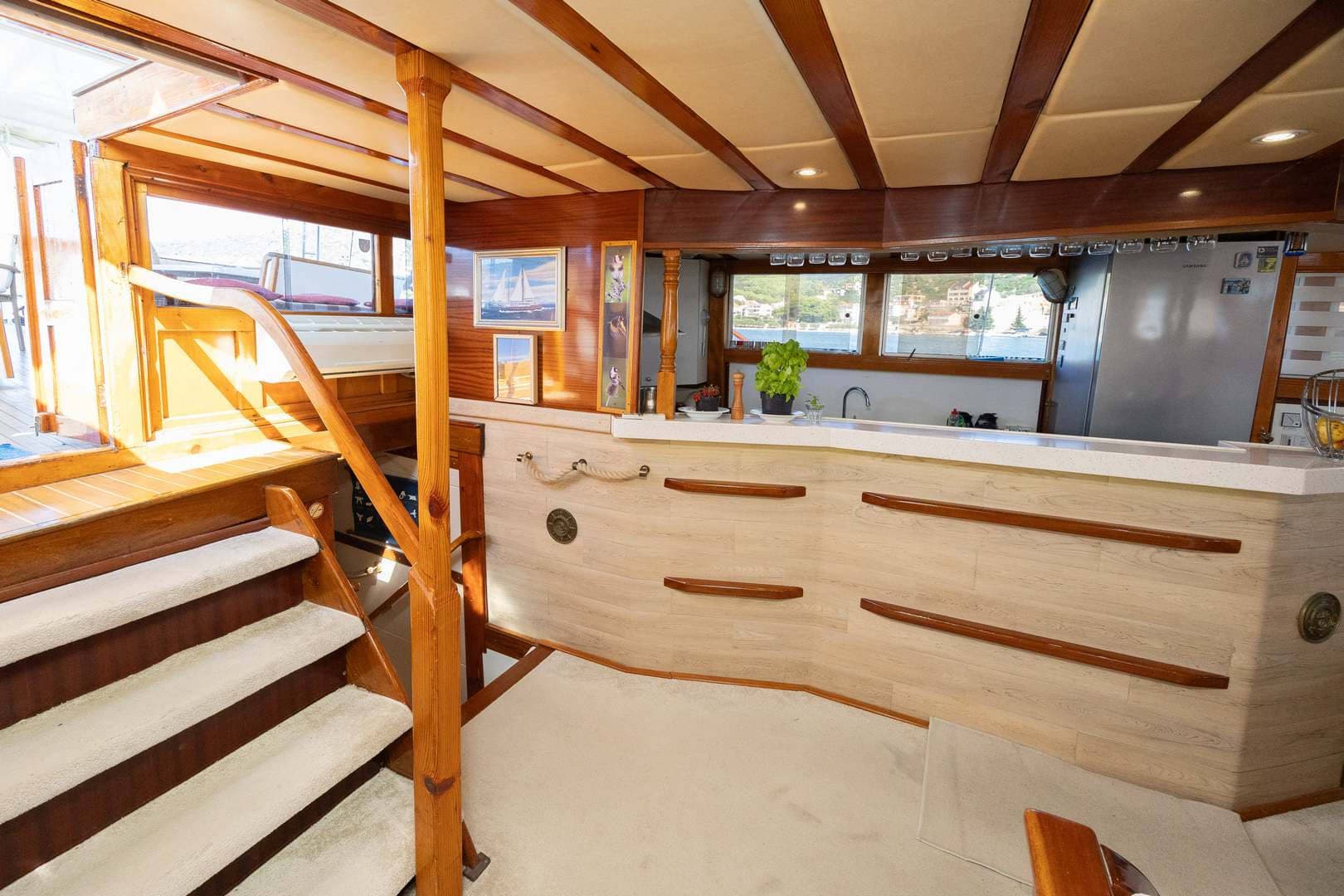 Interior of boat cabin with wood trim, carpeted stairs, and galley area overlooking water.
