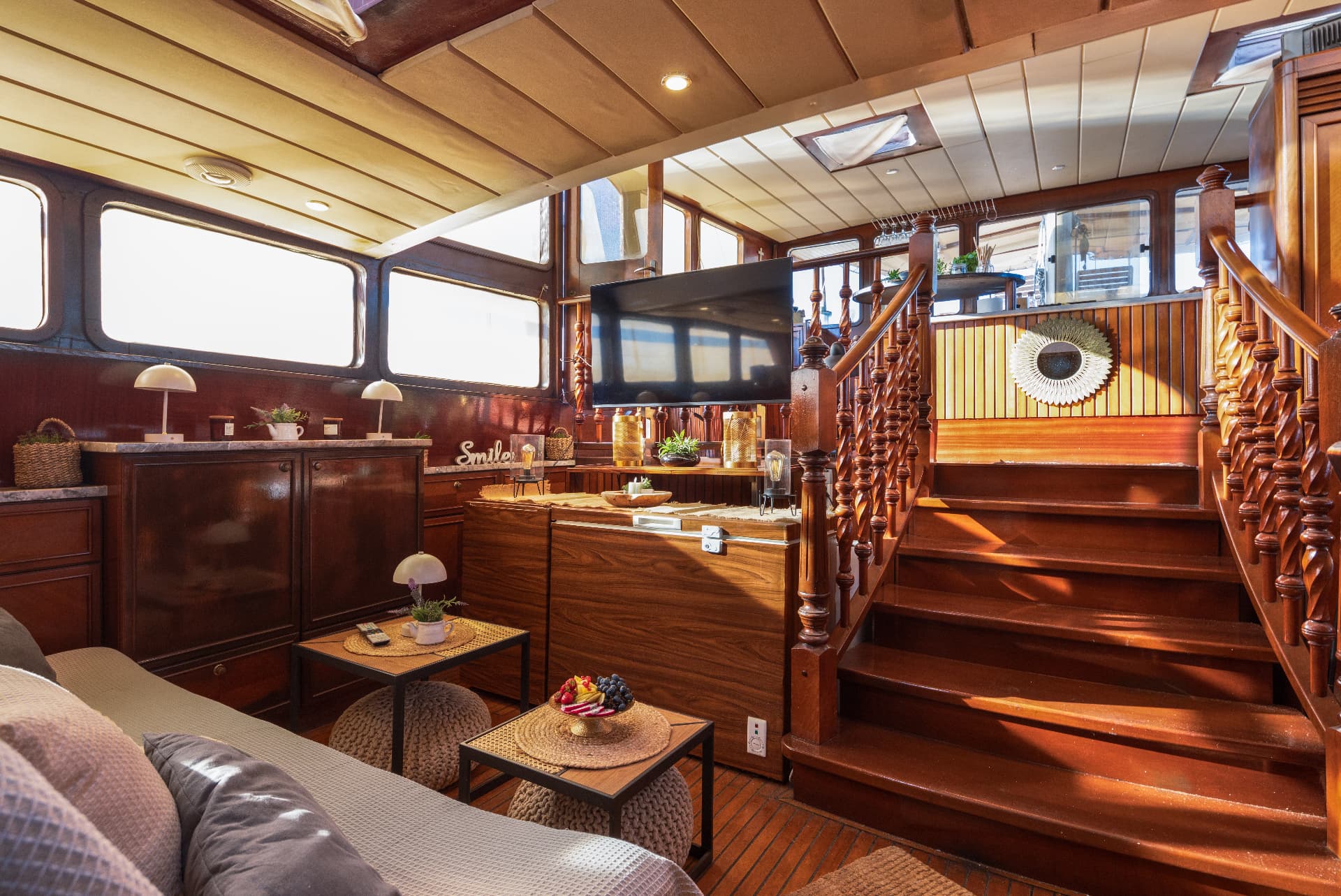 Interior cabin lounge with rich wood paneling, staircase, and seating area on a boat.