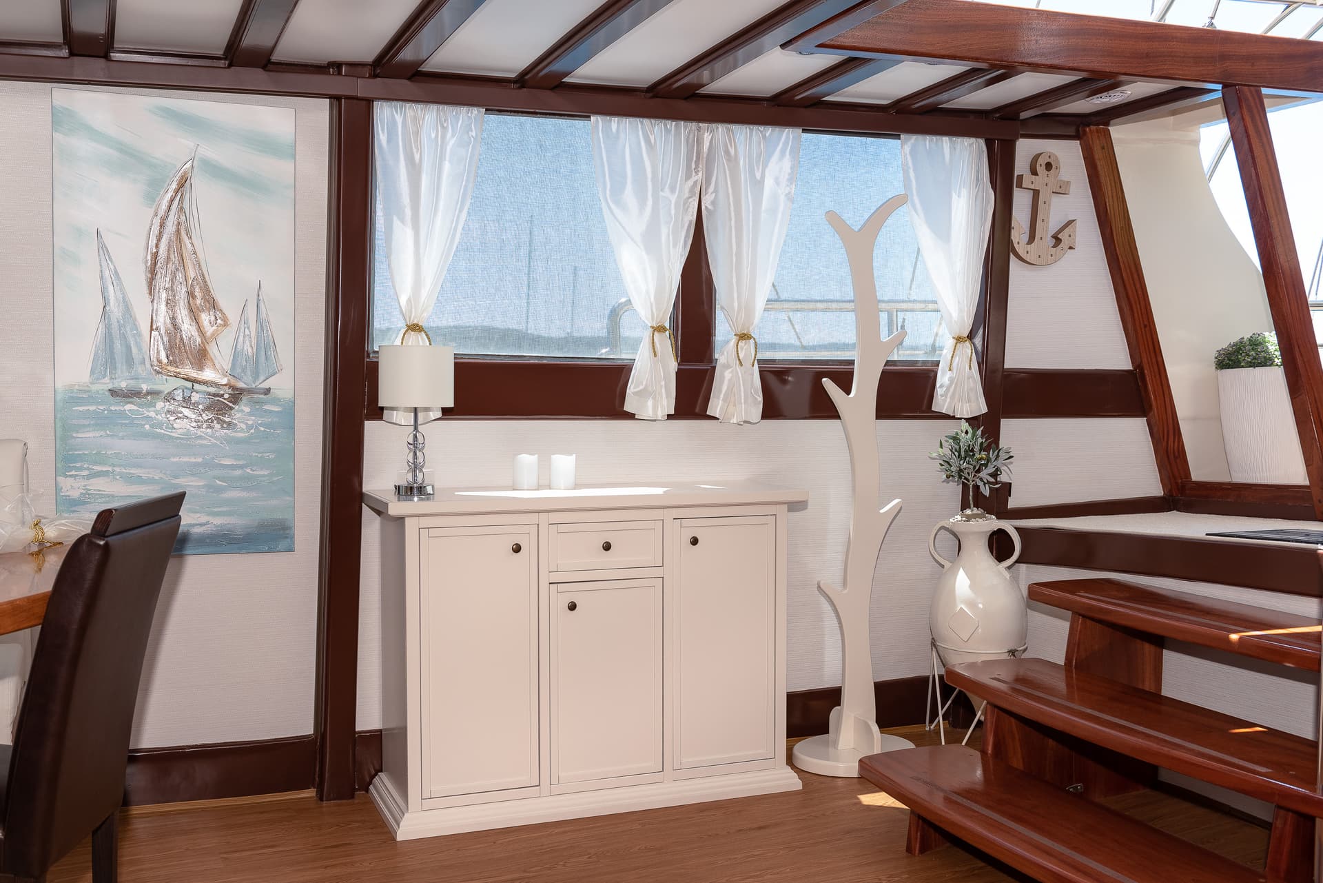 Interior cabin with white nautical decor, sailboat art, and wooden trim, likely on a boat.