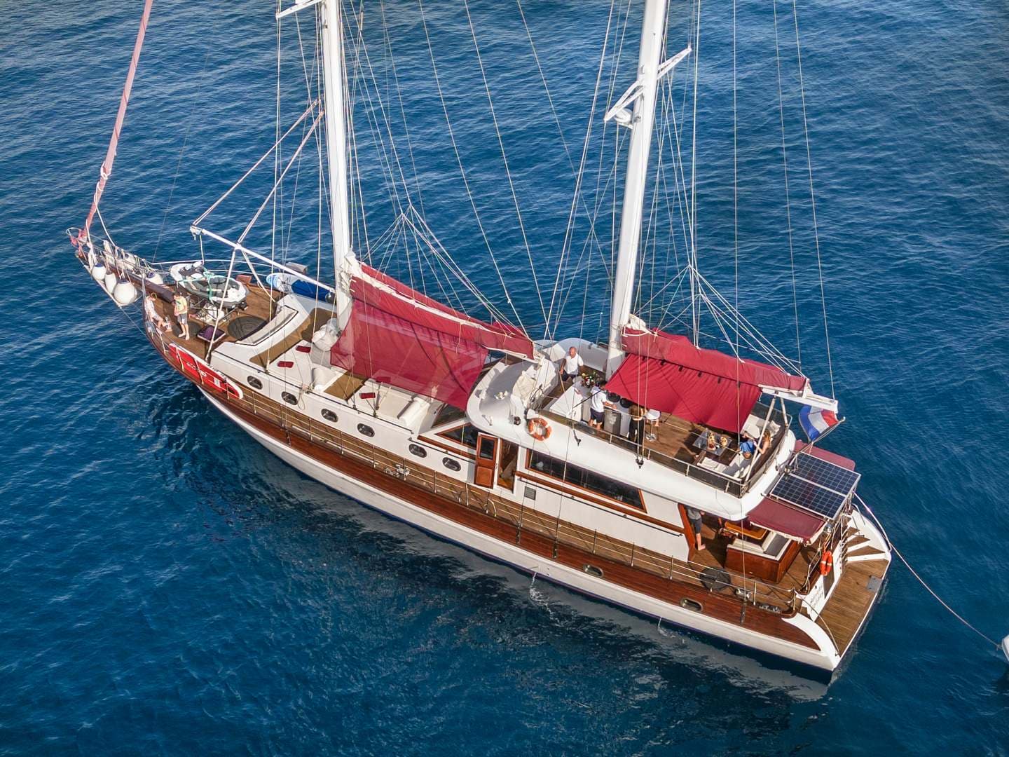 Wooden gulet sailboat with red awnings floating on deep blue sea water