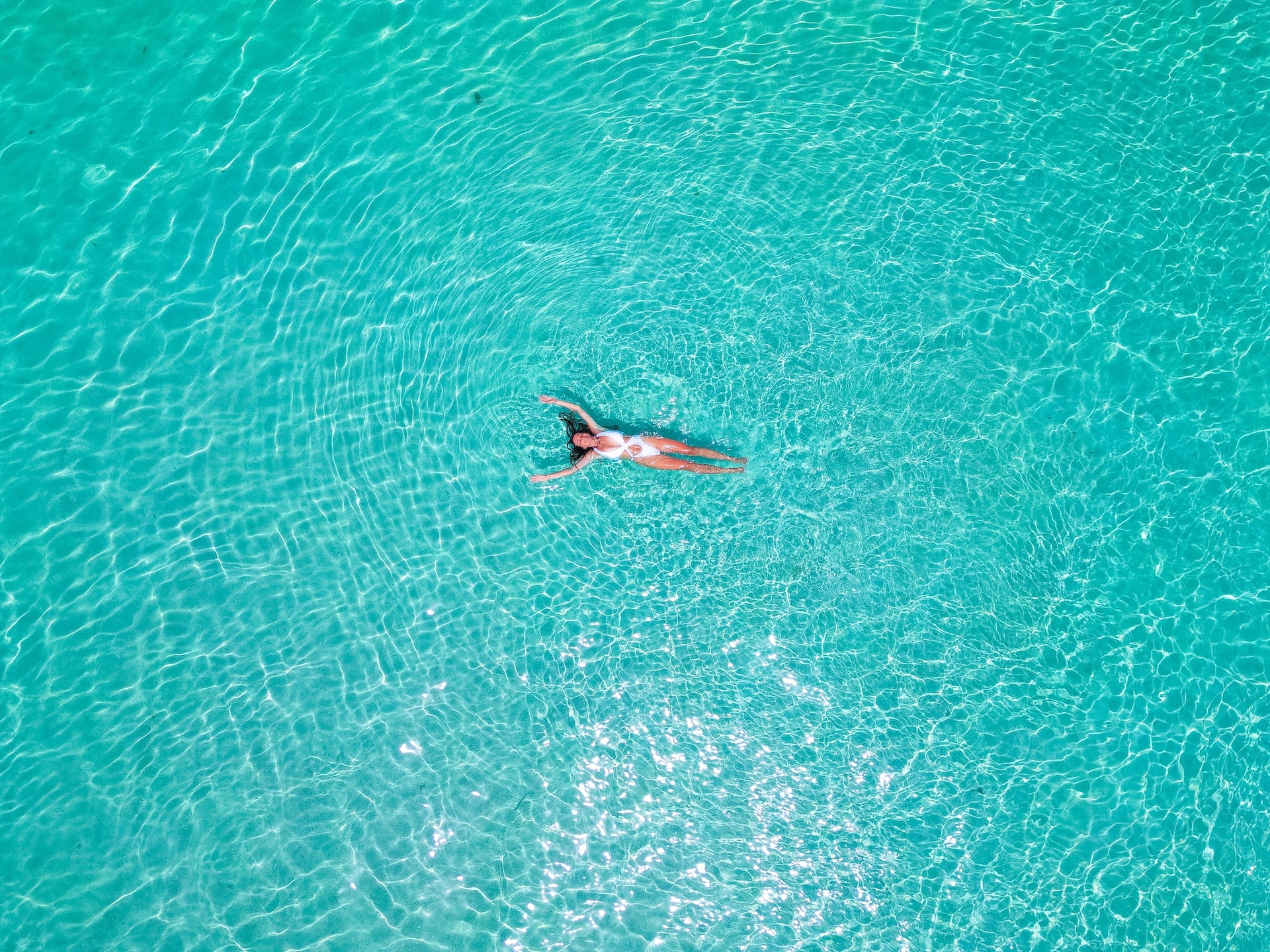 Woman floating on her back in clear turquoise water near Korcula Island.