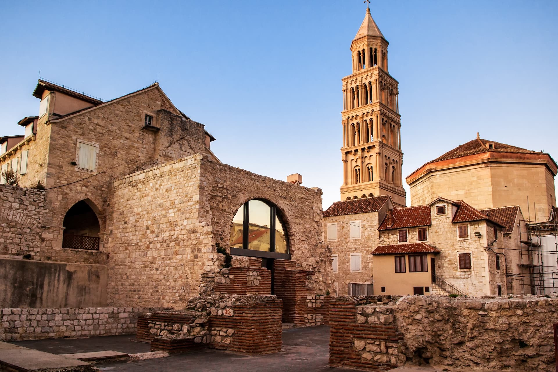 Stone ruins and bell tower of Diocletian's Palace in Split, Croatia, under a clear blue sky.