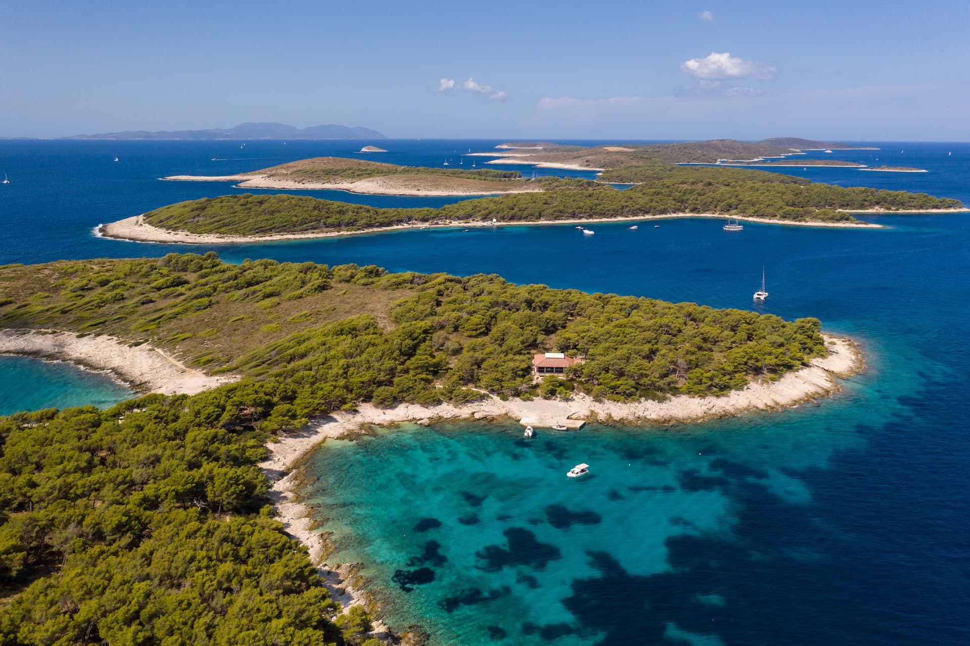 Aerial view of Pakleni Islands near Hvar with turquoise coves and boats on the Adriatic Sea.