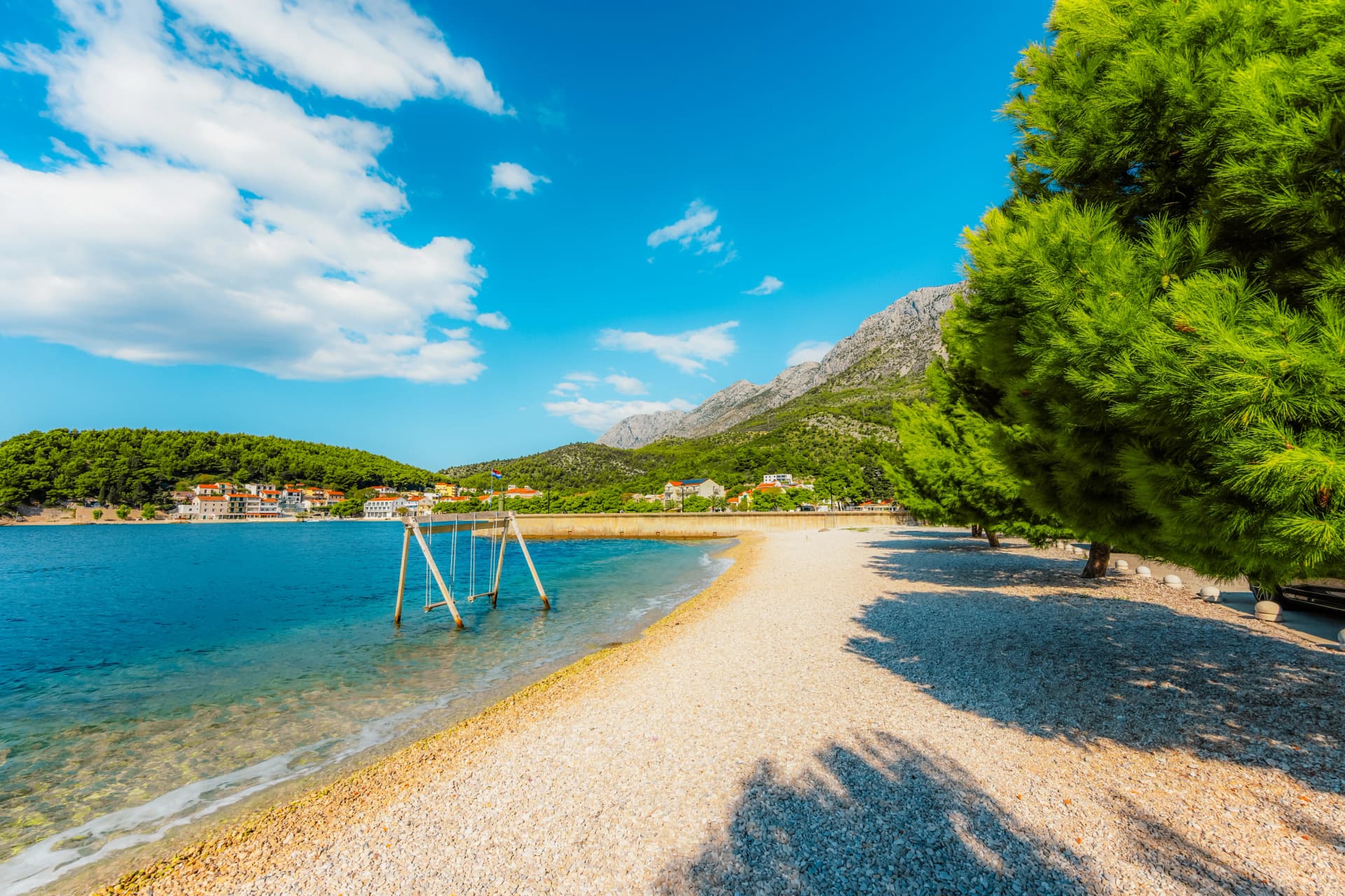 Stunning pebble beach in Drvenik with crystal clear turquoise water and the Biokovo mountain in the Makarska Riviera, Croatia.