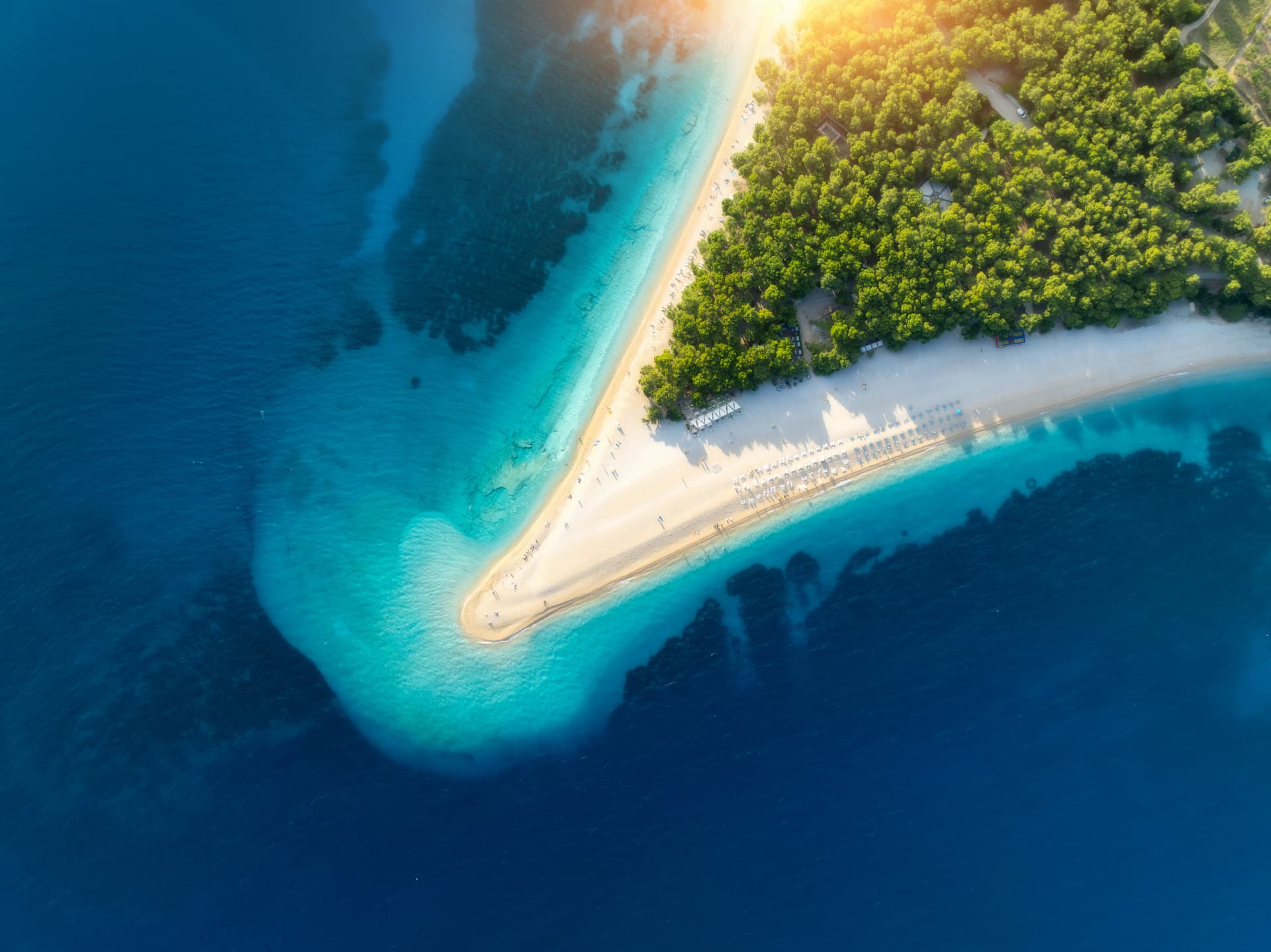 Aerial view of blue sea and Zlatni Rat, Brac island, Croatia in summer. Top drone view of adriatic sea, sandbank, white sandy beach, green trees, azure water at sunset. Tropical landscape. Travel