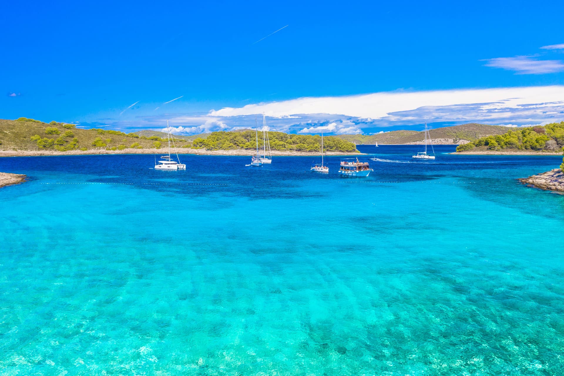 Aerial photo of Pakleni Islands off Hvar coast showing pristine turquoise sea, rugged coastline, lush greenery, hidden coves and crystal-clear Adriatic waters under sunny skies